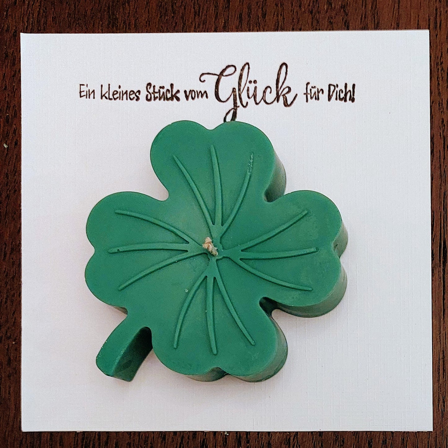 Green four-leaf clover candle on luxurious linnenpaper with text.