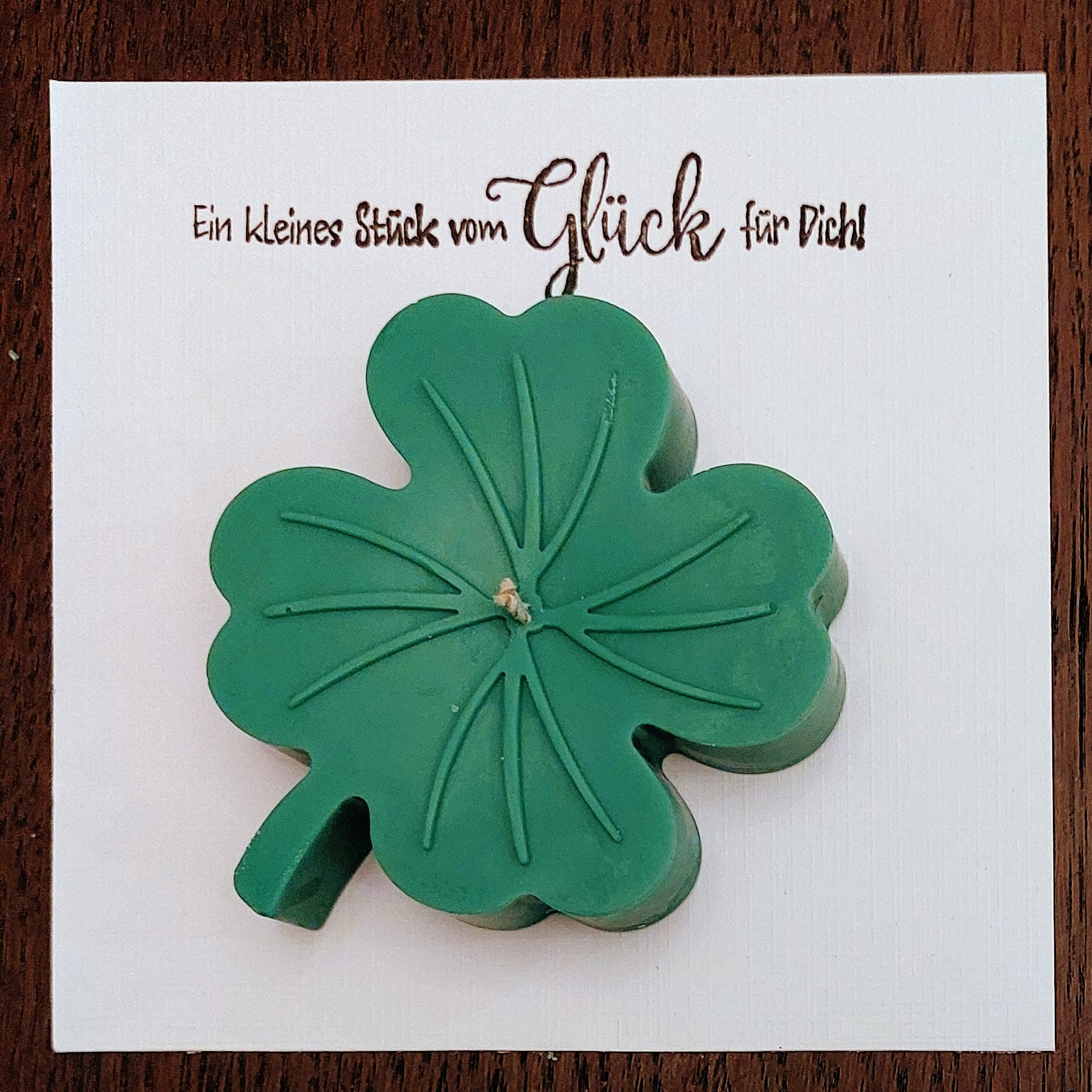 Green four-leaf clover candle on luxurious linnenpaper with text.